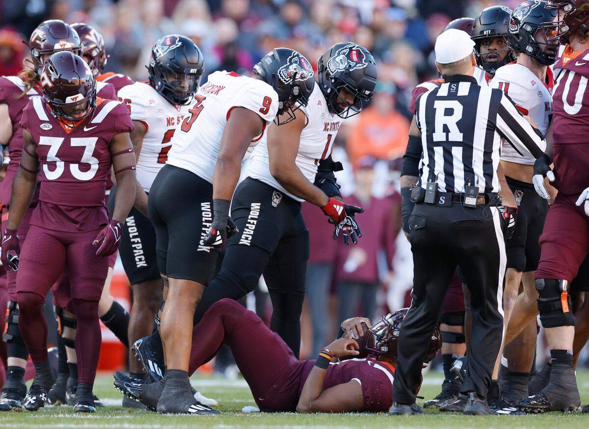 N.C. State’s Savion Jackson (9) and Davin Vann (1) stand over Virginia Tech quarterback Kyron Drones (1) after he was tackled during the first half of N.C. State’s game against Virginia Tech at Lane Stadium in Blacksburg, VA, Saturday, Nov. 18, 2023.