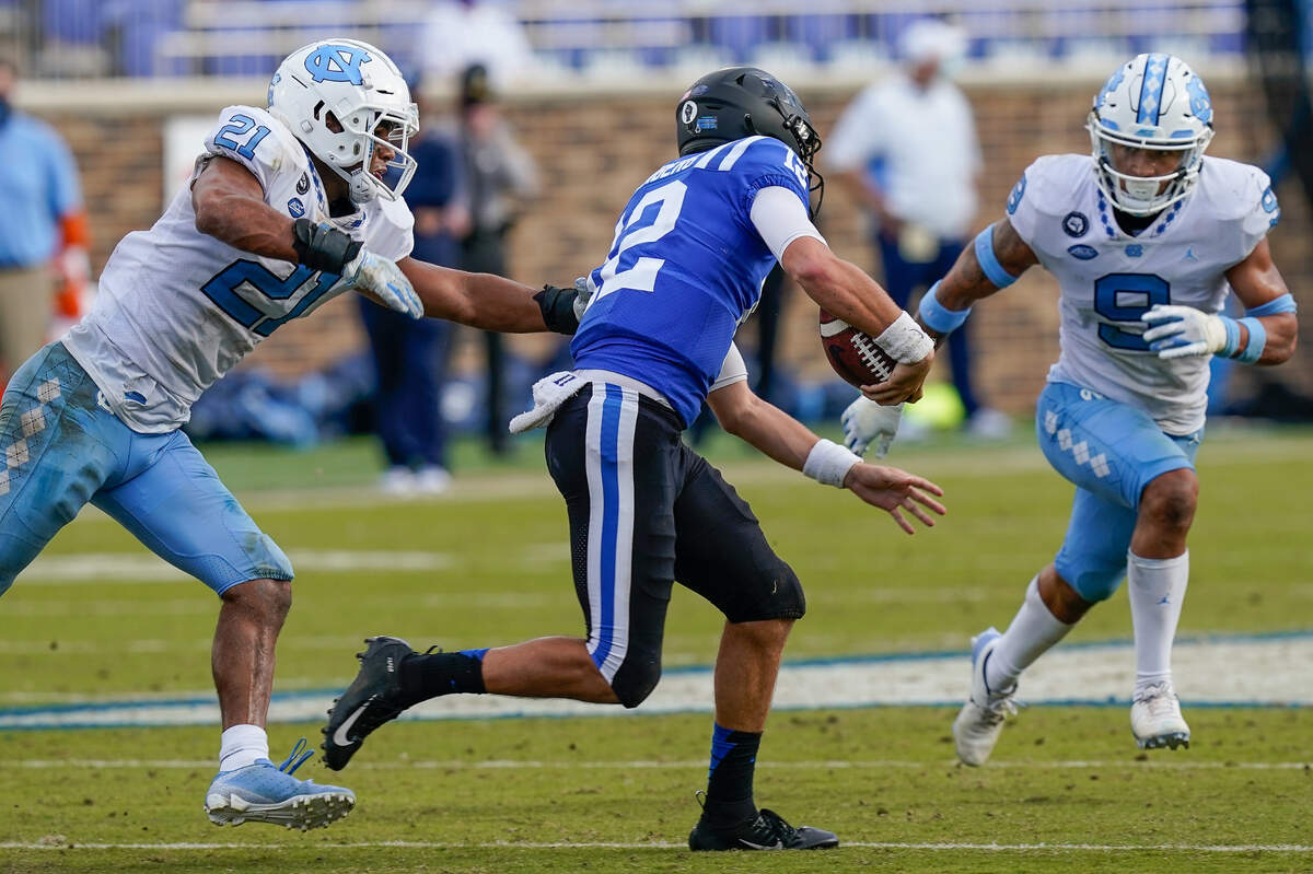 Duke Blue Devils quarterback Gunnar Holmberg (12) is pressured by North Carolina Tar Heels linebacker Chazz Surratt (21) and defensive back Cam’Ron Kelly (9) during the second half at Wallace Wade Stadium. 