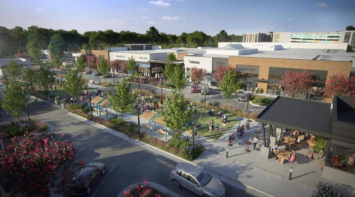 An aerial view shows the new eastern side of the mall at University Place, with the 900 Willow apartment building and parking deck peeking over in the distance. The public green shown in the foreground will be flanked by two retail buildings, with a one-way Main Street wrapping around it.