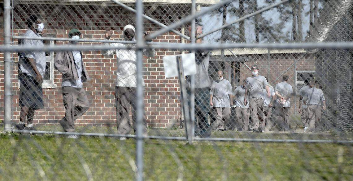 Inmates at the Neuse Correctional Institution in Goldsboro, N.C. move between buildings Sunday morning, April 19, 2020. Some are wearing masks, but incorrectly. more than 280 of 770 inmates at the Eastern North Carolina prison have tested positive for COVID-19, making it one of the hardest-hit prisons in the nation.