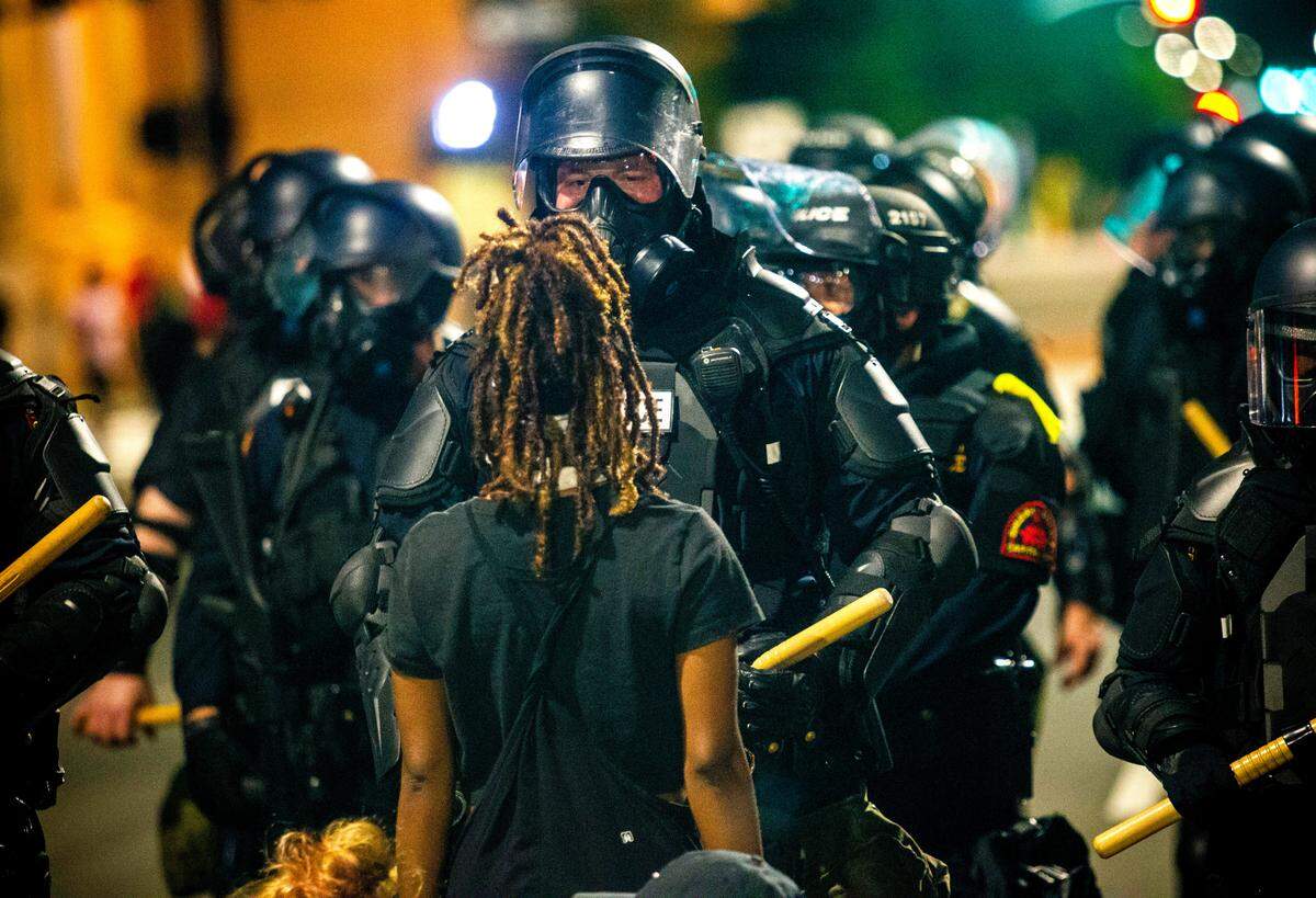 A protester faces off against police in riot gear outside the State Capitol during the second day of protests in Raleigh Sunday night May 31, 2020.