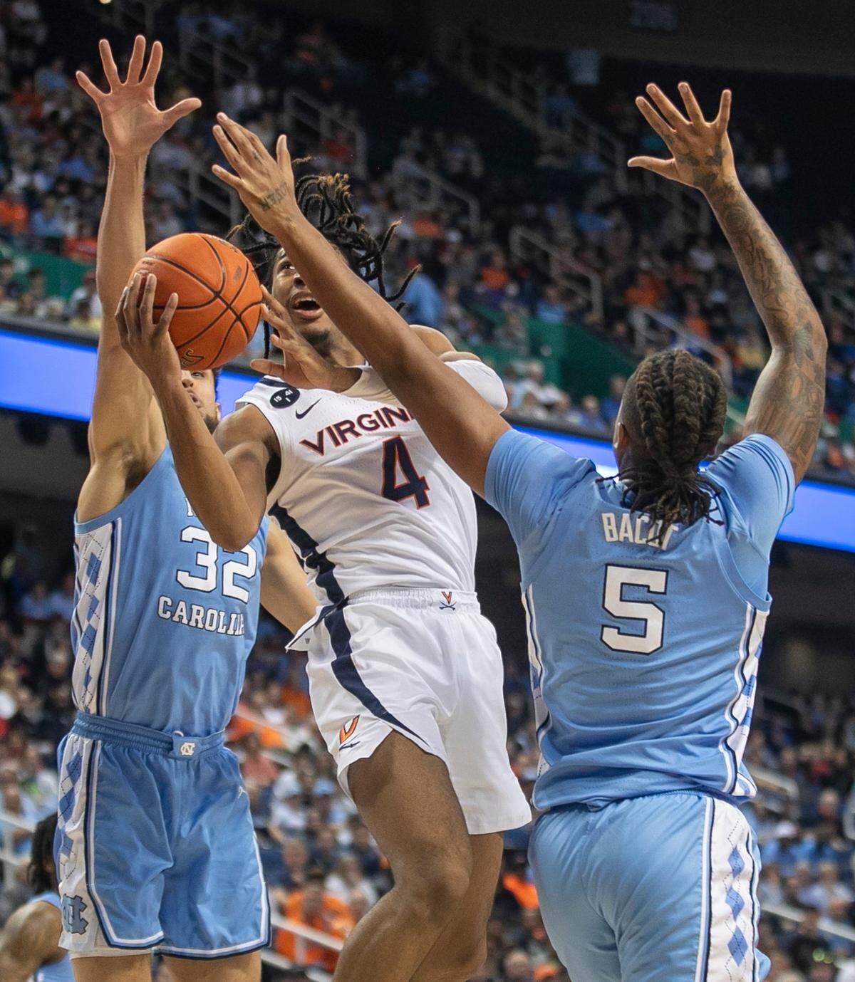 Virginia’s Armaan Franklin (4) drives to the basket against North Carolina’s Pete Nance (32) and Armando Bacot (5) in the first half during the third round of the ACC Tournament on Thursday, March 9, 2023 at the Greensboro Coliseum in Greensboro, N.C.