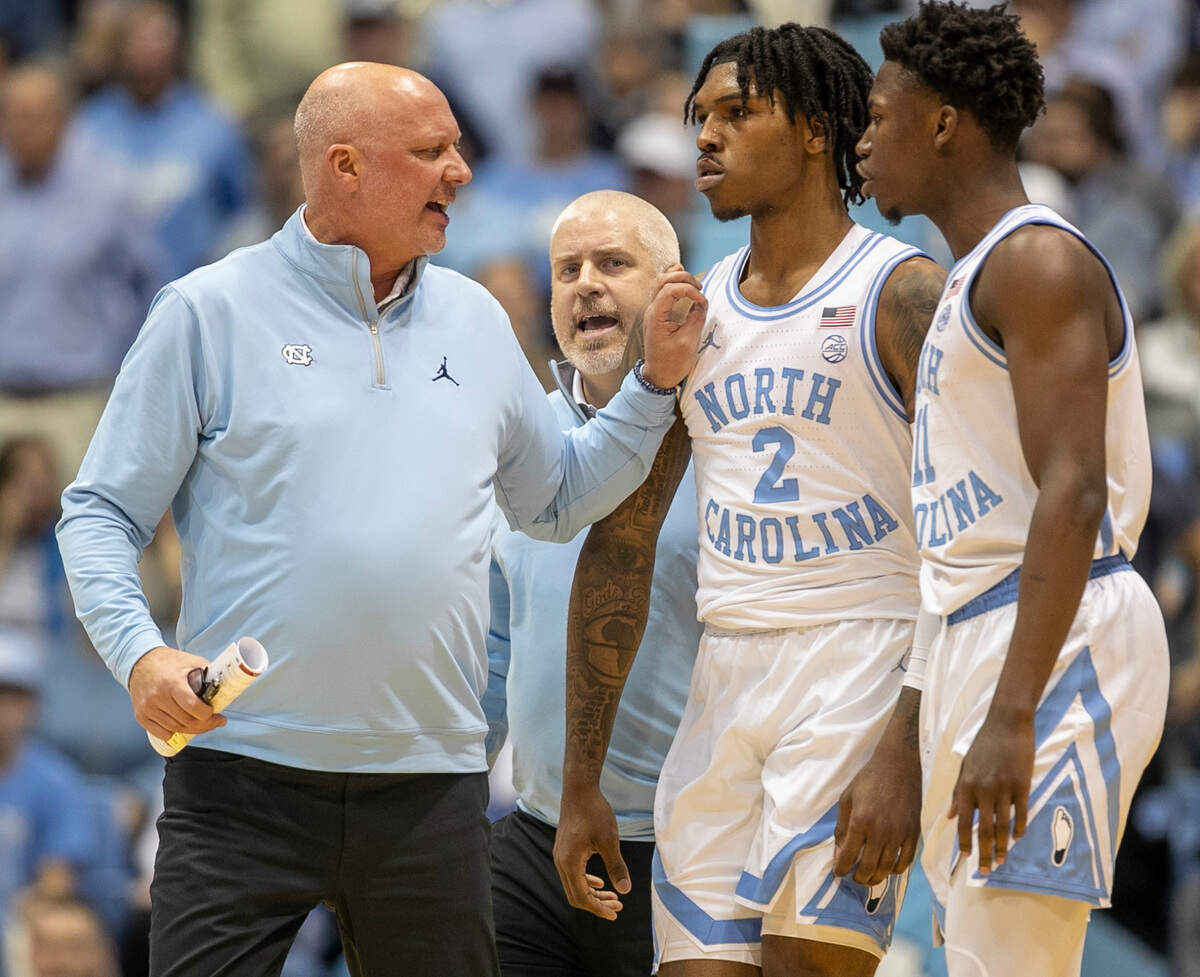 North Carolina assistant coach Jeff Lebo, trainer Doug Halverson and teammate D’Marco Dunn (11) works to calm Caleb Love (2) after an altercation in the second half against N.C. State on Saturday, January 21, 2023 at the Smith Center in Chapel Hill, N.C.