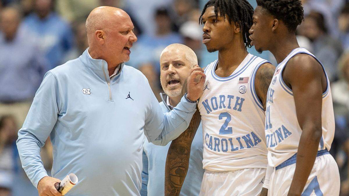 North Carolina assistant coach Jeff Lebo, trainer Doug Halverson and teammate D’Marco Dunn (11) works to calm Caleb Love (2) after an altercation in the second half against N.C. State on Saturday, January 21, 2023 at the Smith Center in Chapel Hill, N.C.