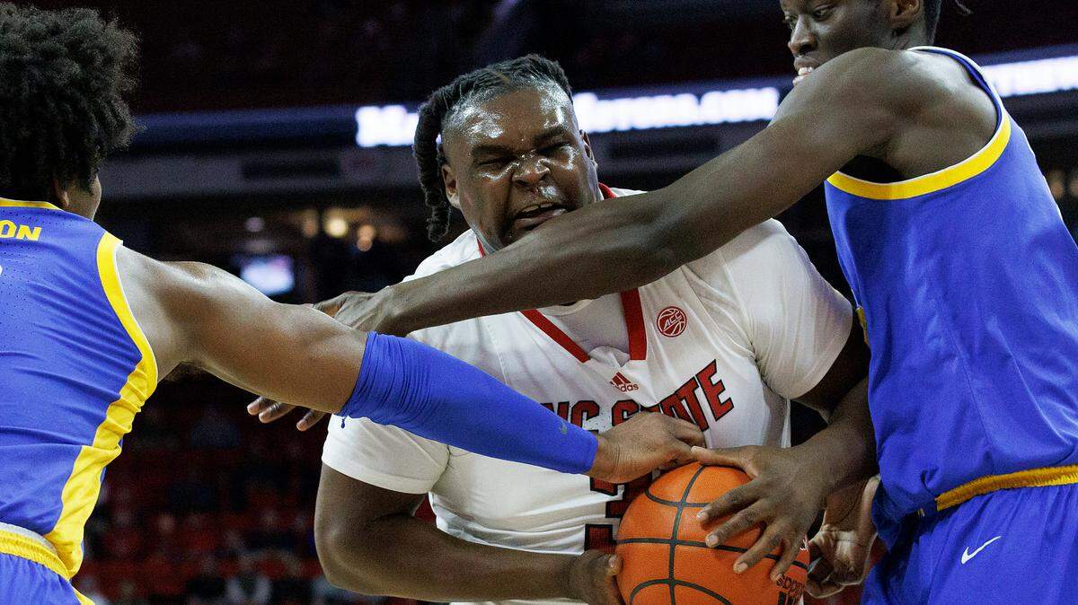 N.C. State’s DJ Burns Jr. drives to the basket past Pittsburgh’s Blake Hinson and Federiko Federiko during the first half of the Wolfpack’s game on Wednesday, Feb. 7, 2024, at PNC Arena in Raleigh, N.C.