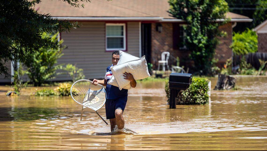 Naser Daher, of Durham’s Old Farm neighborhood, carries his belongings through floodwaters near the Eno River in Durham on Monday morning, July 7, 2025, after heavy rain from Tropical Storm Chantal caused flash flooding. Daher and his brother said they escaped the home with four children in the middle of the night as floodwater poured in.