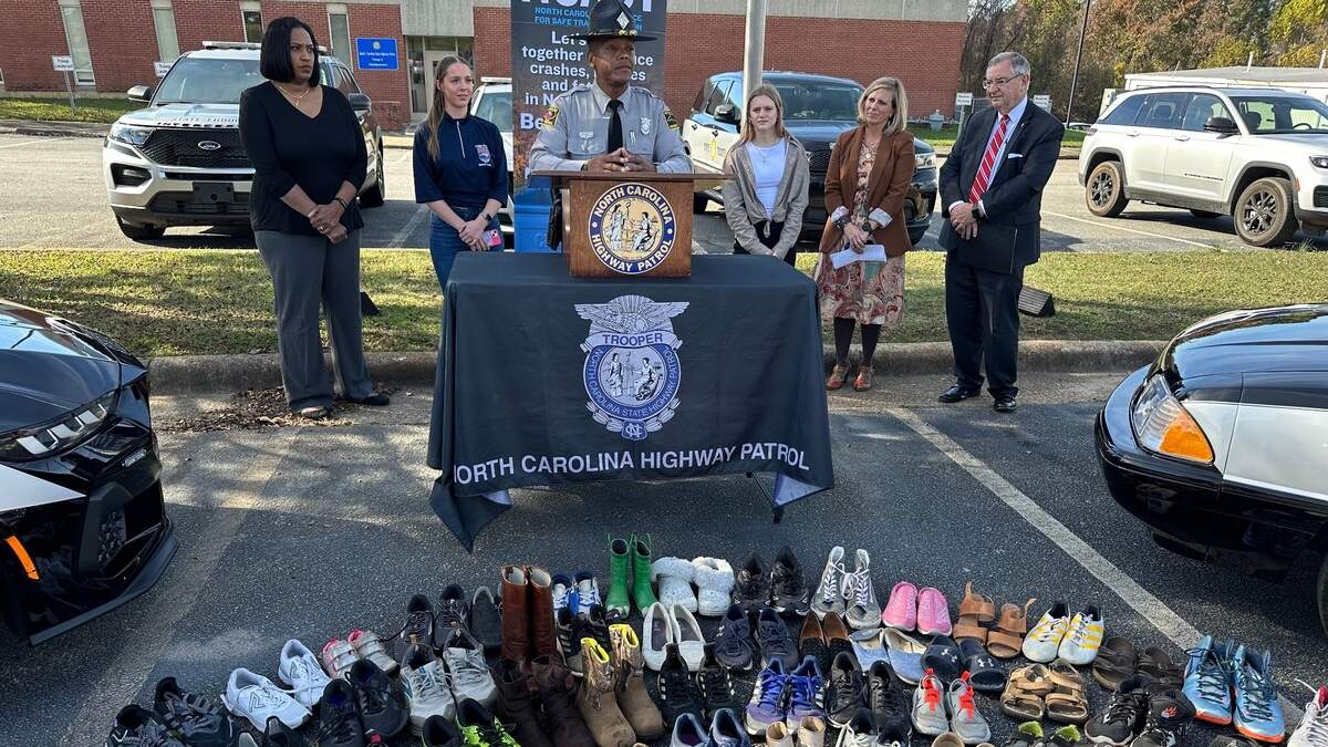 J.J. Garrett, a traffic safety information officer for the N.C. State Highway Patrol, speaks at a World Day of Remembrance event in Raleigh on Sunday, Nov. 17, 2024. In front of Garrett are shoes, a pair for each of the 165 people under the age of 20 killed on car crashes in North Carolina last year.