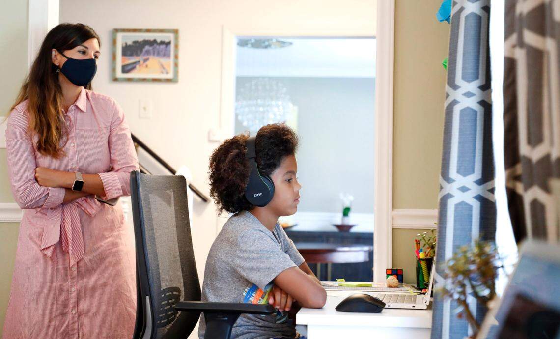 As his mother Juliette takes a peek, Harper Grimmett attends his day of classes as a sixth grader at Ligon Middle School while at their home in Raleigh, N.C. Monday, August 17, 2020.