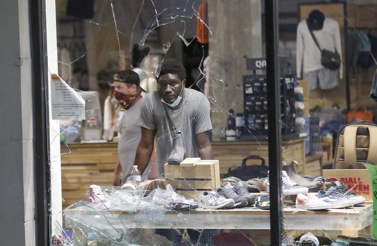 An employee stands in Apex Outfitter and Board Company to help protect the shop during a protest in downtown Raleigh, N.C. Saturday, May 30, 2020.
