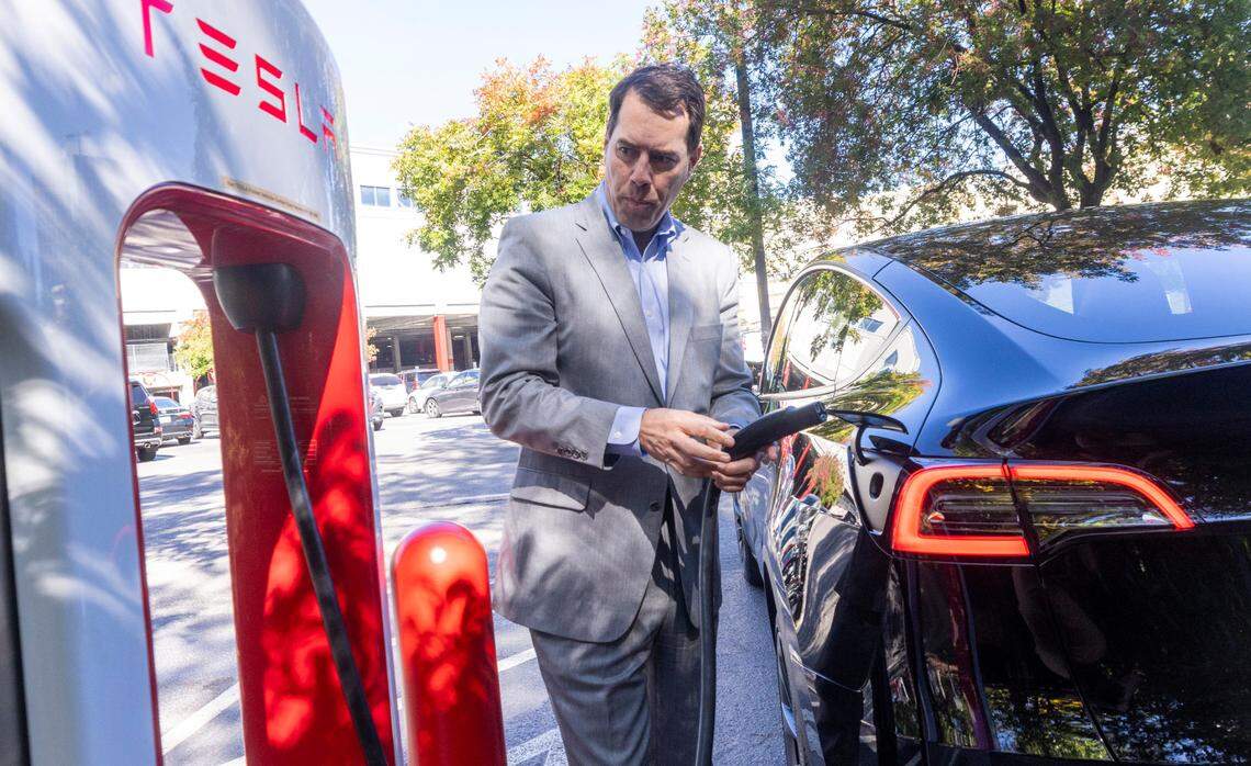 Aaron Landry of Pinehurst finishes charging his Model Y Tesla at an electric charging station at North Hills in Raleigh Tuesday, October. 17, 2023. Electric vehicle owners will see an increase in both new vehicle and annual registration fees. 