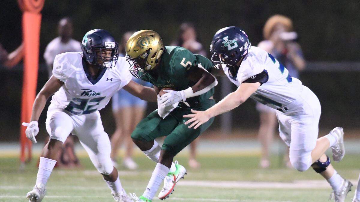 Jacob Gill (5) of Cardinal Gibbons is brought down by B.J. Adamchik, right, and Corey Ibrahim (22) of Leesville Road. The Leesville Road Pride visited the Cardinal Gibbons Crusaders in a high school football game on September 27, 2019.