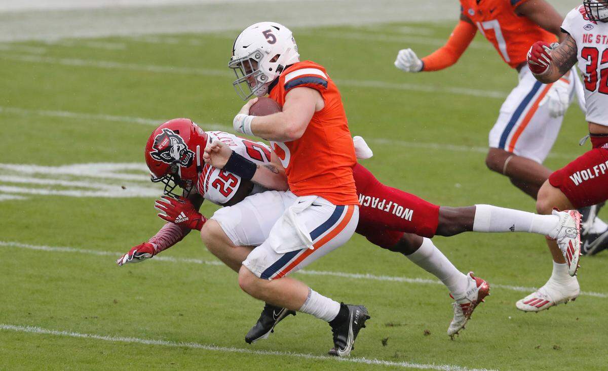 N.C. State cornerback Shyheim Battle (25) sacks Virginia quarterback Brennan Armstrong (5) for a ten-yard loss during the first half of N.C. State’s game against Virginia at Scott Stadium in Charlottesville, Va., Saturday, Oct. 10, 2020. Armstrong has transferred to N.C. State for the 2023 season.