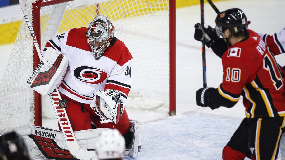 Carolina Hurricanes goalie Petr Mrazek, left, of the Czech Republic, grabs for the puck as Calgary Flames’ Derek Ryan closes in during third period NHL hockey action in Calgary, Tuesday, Jan. 22, 2019. (Jeff McIntosh/The Canadian Press via AP)