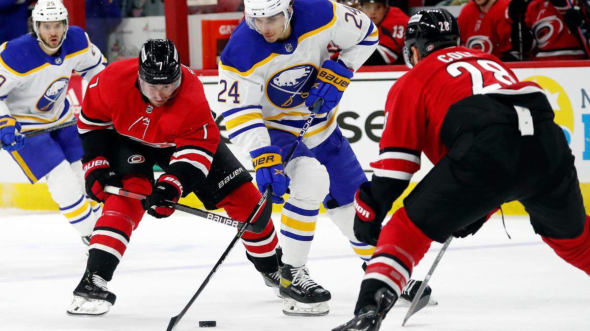 Buffalo Sabres’ Dylan Cozens (24) maintains control of the puck between Carolina Hurricanes’ Brendan Smith (7) and Ian Cole (28) during the first period of an NHL hockey game in Raleigh, N.C., Thursday, April 7, 2022. (AP Photo/Karl B DeBlaker)