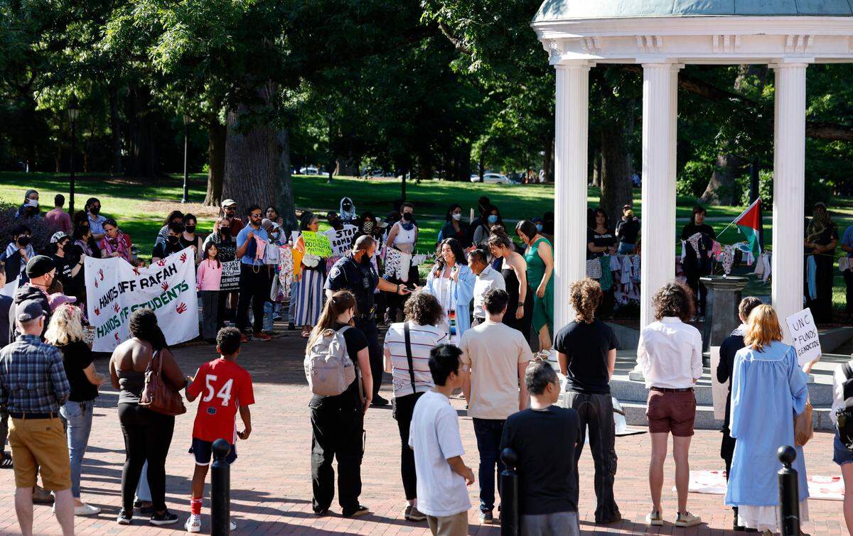 Graduates get their photos taken at the Old Well as pro-Palestinian demonstrators surround it at UNC Chapel Hill in Chapel Hill, N.C., Saturday, May 11, 2024.