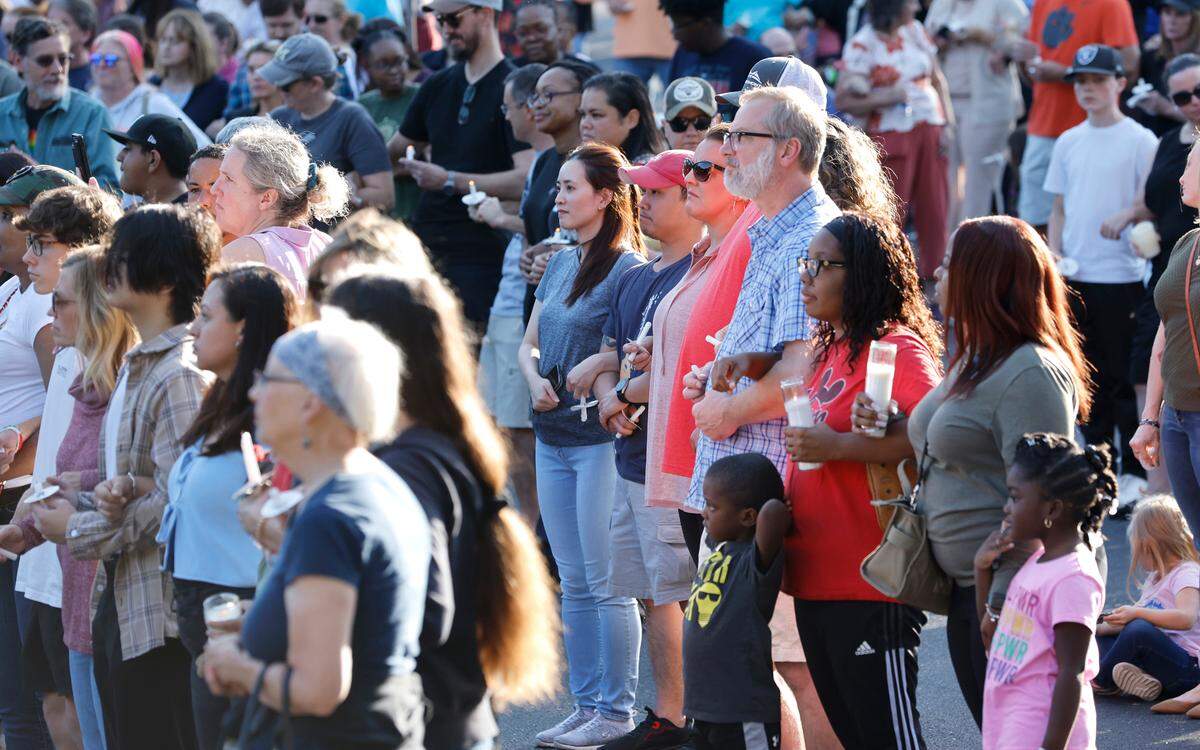 Attendees lock arms in unity during a candlelight vigil Saturday, Oct.15, 2022, for those killed and wounded Thursday in a mass shooting in the Hedingham neighborhood in Raleigh, N.C.