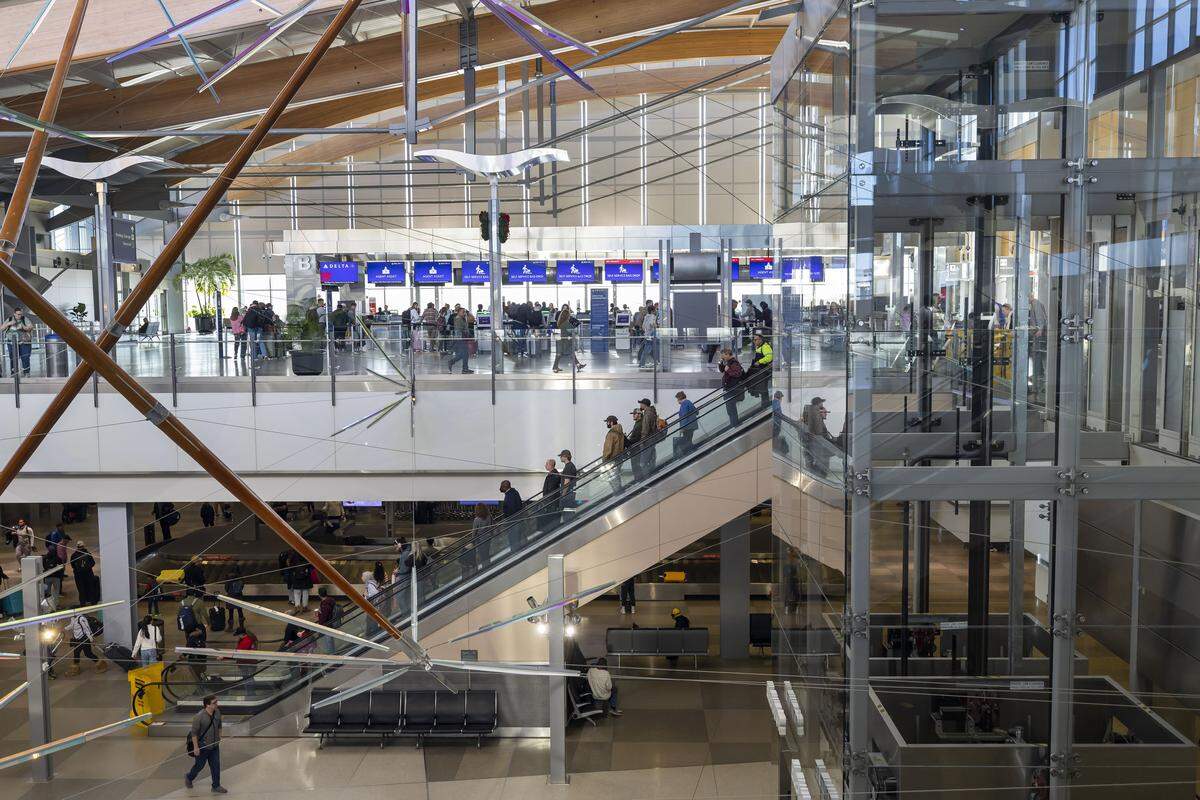 Arriving passengers use escalators to move toward baggage claim in the lower level of Terminal 2 at RDU International airport on Friday, December 19, 2025 in Morrisville, N.C. 