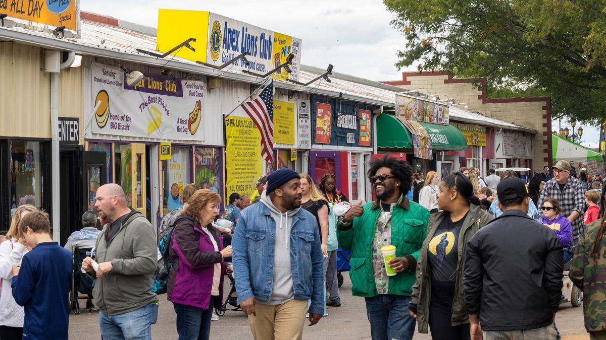 Fair-goers walk past the Apex Lions Club restaurant during the State Fair in Raleigh Monday, Oct. 16, 2023. The Apex Lions Club has been serving food at the fair’s restaurant row since 1943. The restaurant row building will be replaced with an events center next year.