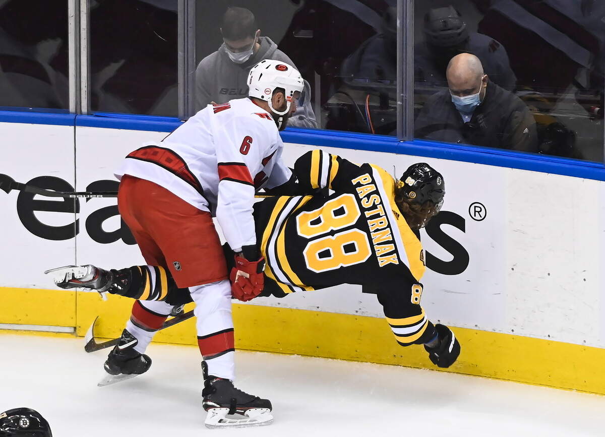 Carolina Hurricanes defenseman Joel Edmundson (6) hits Boston Bruins right wing David Pastrnak (88) during the first period of an NHL hockey Eastern Conference Stanley Cup playoff game in Toronto, Wednesday, Aug. 12, 2020. (Nathan Denette/The Canadian Press via AP)