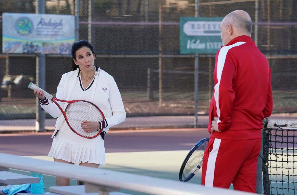 Michaela Watkins as Delia and Rob Corddry as Forrest play tennis in a location meant to represent a court at a Raleigh park in a scene from “The Unicorn” on CBS.