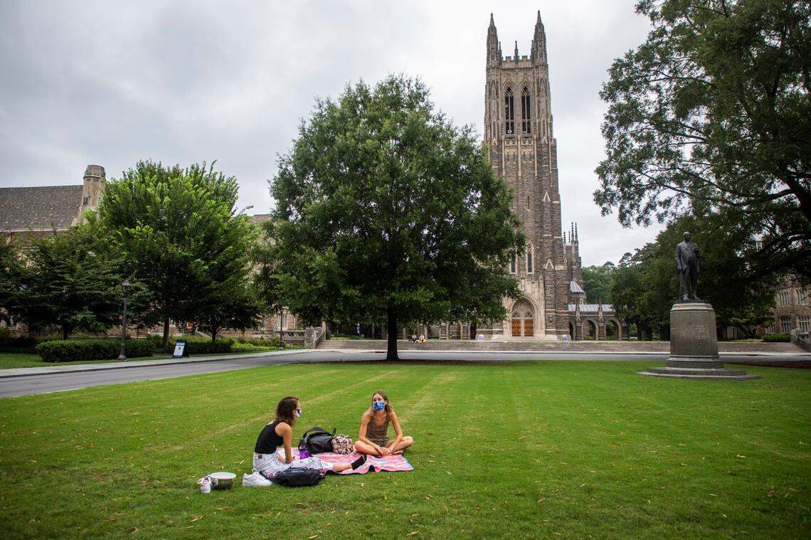 Students Molly Monsour, left, and Madeleine Yancy share a socially-distanced visit with masks to prevent the spread of COVID-19 on the lawn in front of Duke Chapel at Duke University on Tuesday, Sept. 1, 2020, in Durham, N.C.