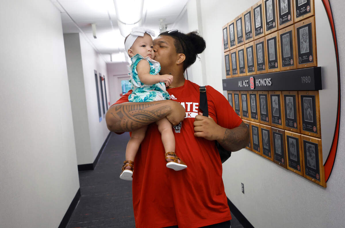 N.C. State defensive lineman Joshua Harris walks through the Murphy Center with his 9-month-old daughter Aylah in Raleigh, N.C., Thursday, June 16, 2022.
