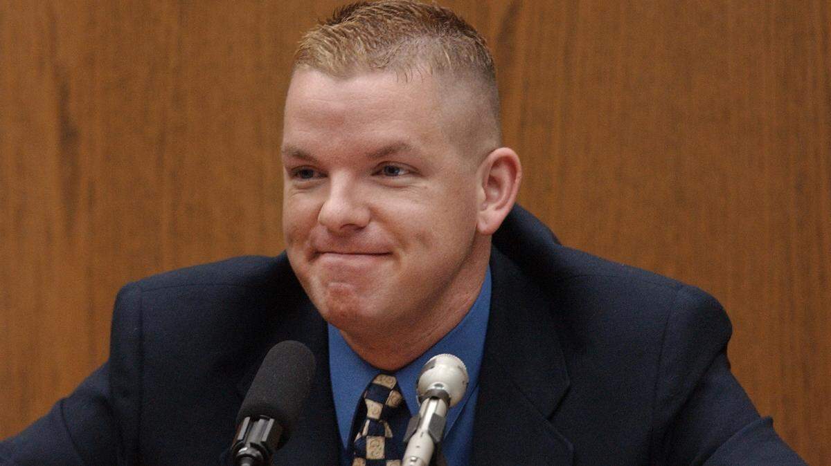 Self-described male escort Brent Wolgamott, 28, of Raleigh, N.C., grins at defense attorney David Rudolf after saying some of his "clients" were doctors and lawyers and even one judge during his testimony Monday in the Michael Peterson murder trial.