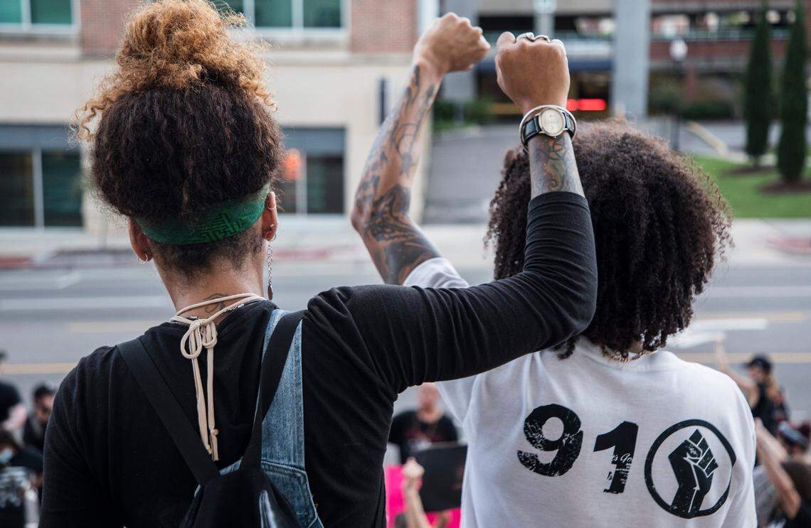 Lily Nicole, left, and Brandon Cagle, right, board members of an organization called “the lowercase leaders” that hosts daily demonstrations outside City Hall in downtown Wilmington, N.C., hold their fists up during a moment of silence outside of City Hall on Thursday, June 25, 2020.