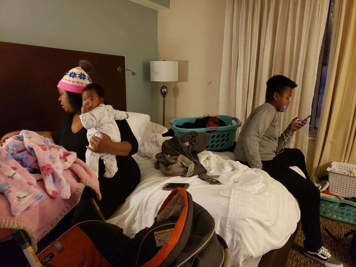 Samanther Crowder reaches for something for her 5-month-old baby as her son Jayden Crowder, 12, plays on his phone waiting for his ride to school on Monday, Jan. 27, 2019.  