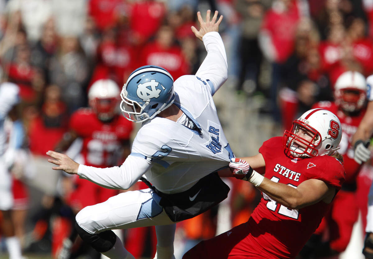 N.C. State’s Audie Cole (42) brings down UNC’s quarterback Bryn Renner (2) as Renner fumbles the ball during the first half of N.C. State’s game against UNC Saturday November 5, 2011, at Carter-Finley Stadium, in Raleigh, N.C.
