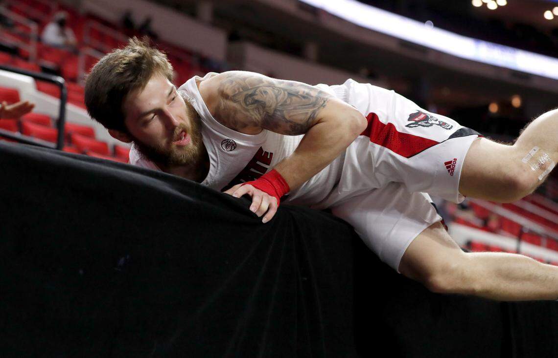 N.C. State’s Braxton Beverly (10) looks back at the court after almost going over the barrier while chasing a loose ball during the first half of N.C. State’s game against Campbell at PNC Arena in Raleigh, N.C., Saturday, Dec. 19, 2020.