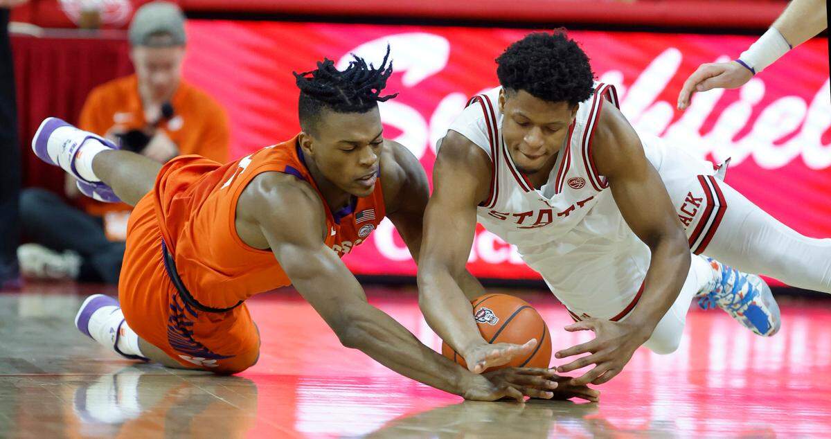 Clemson’s RJ Godfrey (22) and N.C. State’s LJ Thomas (4) go after the loose ball during the first half of N.C. State’s game against Clemson at PNC Arena in Raleigh, N.C., Saturday, Feb. 25, 2023.