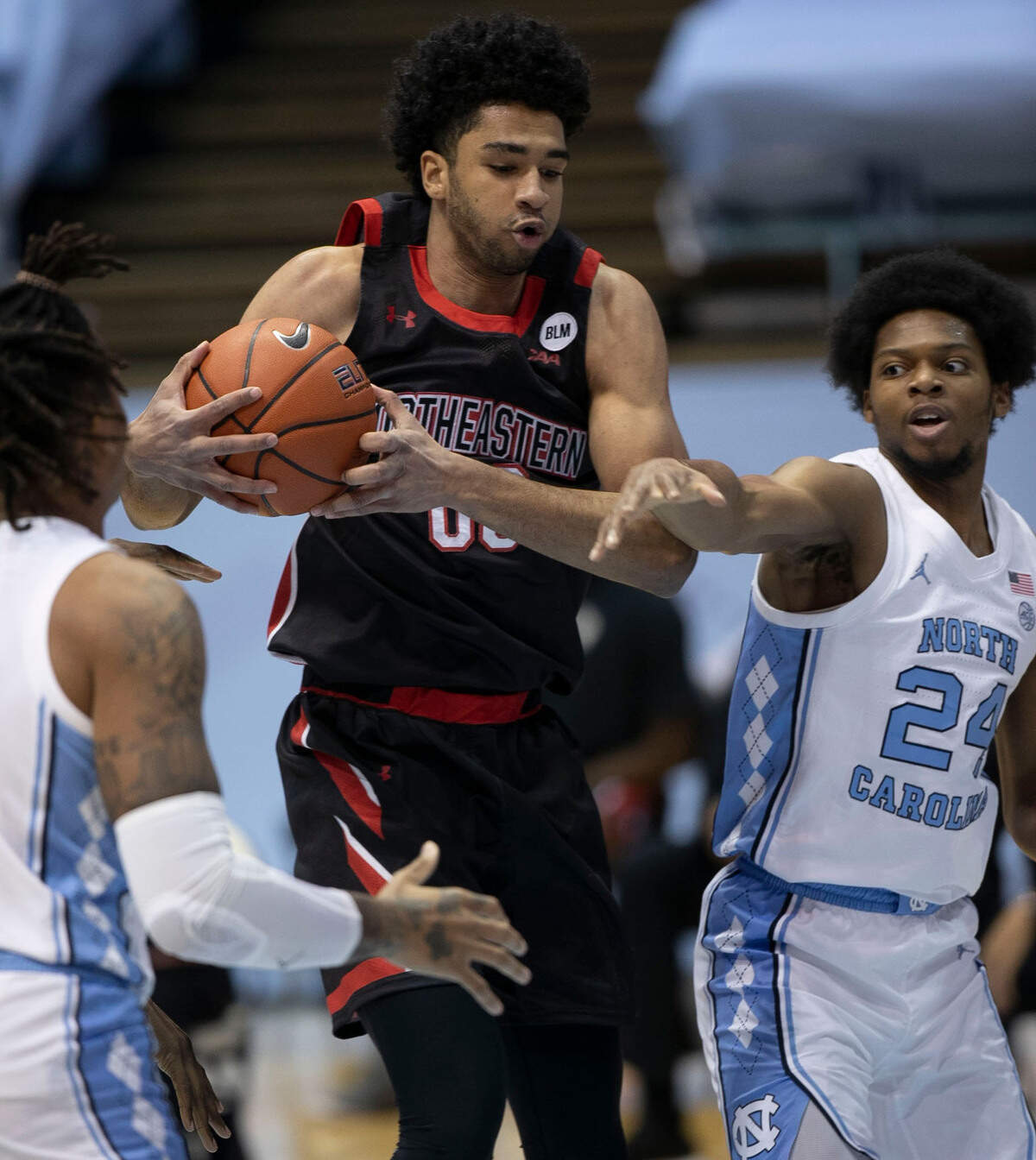 Northeastern’s Jason Strong (00) secures a rebound over North Carolina’s Kerwin Walton (24) during the first half on Wednesday, February 17, 2021 at the Smith Center in Chapel Hill, N.C.