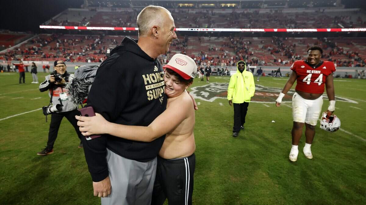 Jackston McDuffie, 12, hugs head coach Dave Doeren after the Wolfpack’s 21-11 victory over Florida State at Carter-Finley Stadium in Raleigh, N.C., Friday, Nov. 21, 2025.