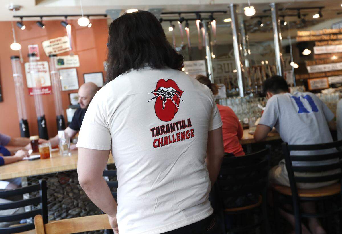 Mark Christmann of Greensboro wears his Tarantula Challenge t-shirt after finishing a Tarantula Burger at Bull City Burger and Brewery in Durham, N.C., Thursday, April 19, 2018. The burger is a 6 oz. pasture-raised NC beef burger, with gruyere cheese, spicy chili sauce and an oven-baked tarantula.