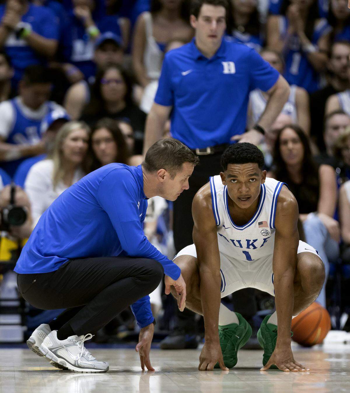 Duke coach Jon Scheyer talks with guard Caleb Foster (1) after an injury in the first half against North Carolina on Saturday, March 7, 2026 at Cameron Indoor Stadium in Durham, N.C. Foster did not return to play and was in a boot on the bench in the second half.