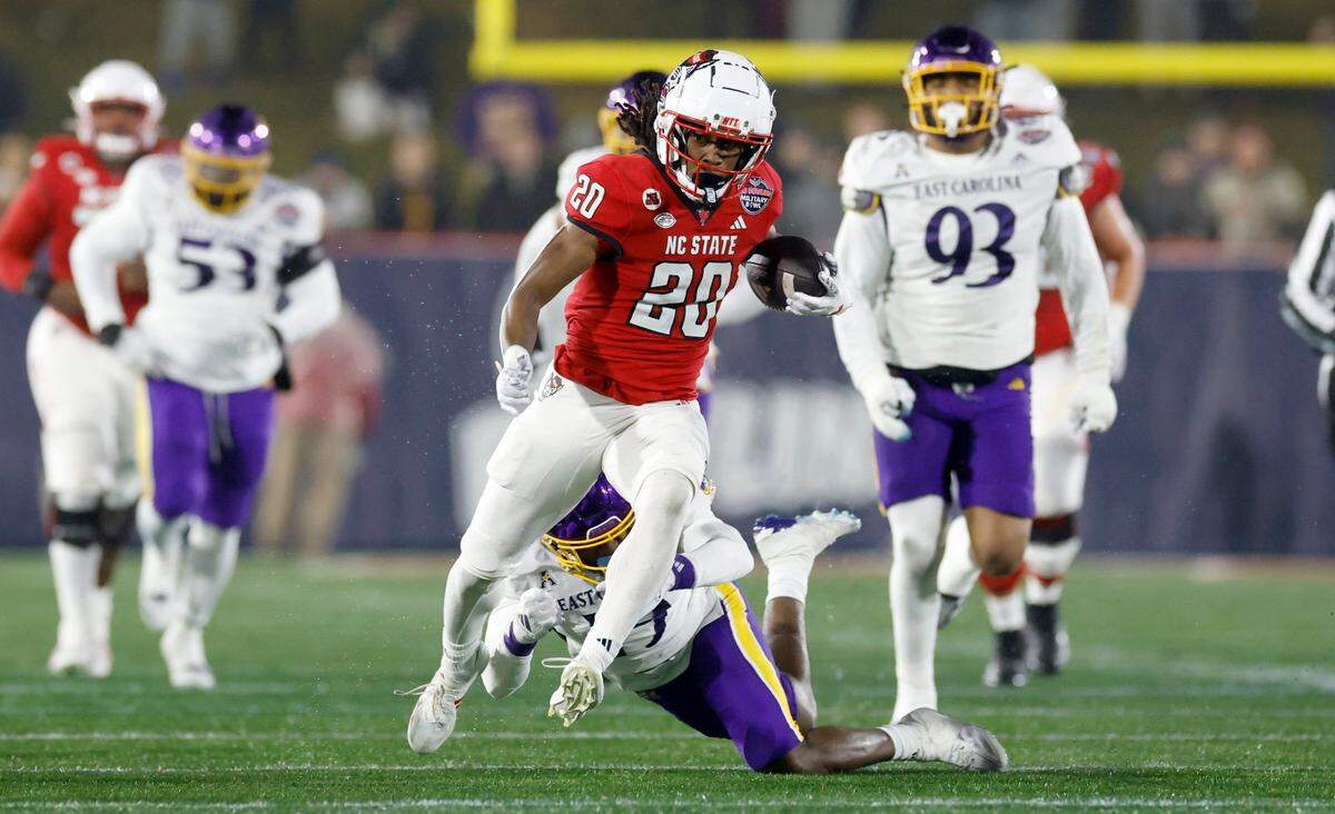 N.C. State running back Hollywood Smothers (20) runs by East Carolina defensive back DeMarius Hines (19) on a long gain during the first half of N.C. State’s game against ECU in the Military Bowl at Navy-Marine Corps Memorial Stadium in Annapolis, Md., Saturday, Dec. 28, 2024.