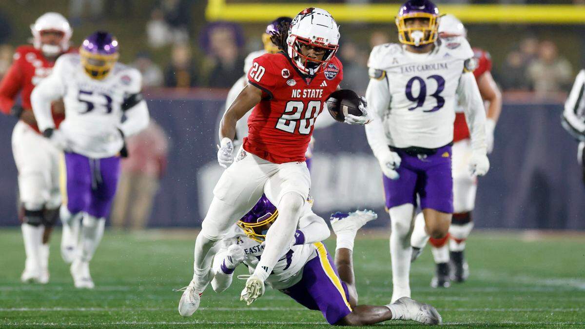 N.C. State running back Hollywood Smothers (20) runs by East Carolina defensive back DeMarius Hines (19) on a long gain during the first half of N.C. State’s game against ECU in the Military Bowl at Navy-Marine Corps Memorial Stadium in Annapolis, Md., Saturday, Dec. 28, 2024.