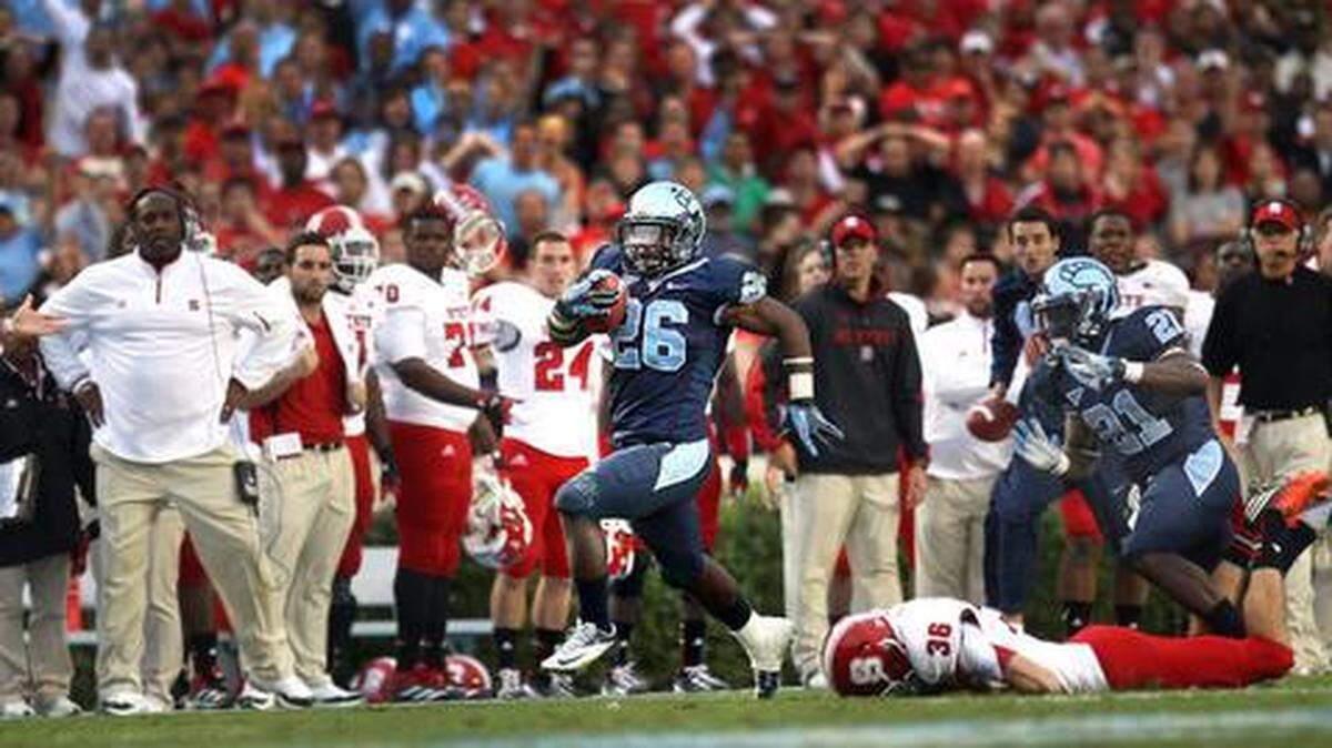 UNC’s Giovani Bernard (26) breaks away from N.C. State’s Will Baumann (36) as he races in front of the Wolfpack bench during a 74-yard punt return to score the game winning touchdown with :13 seconds to play, securing a 43-35 victory over N.C. State on Saturday October 27, 2012 at Kenan Stadium in Chapel Hill, N.C.
