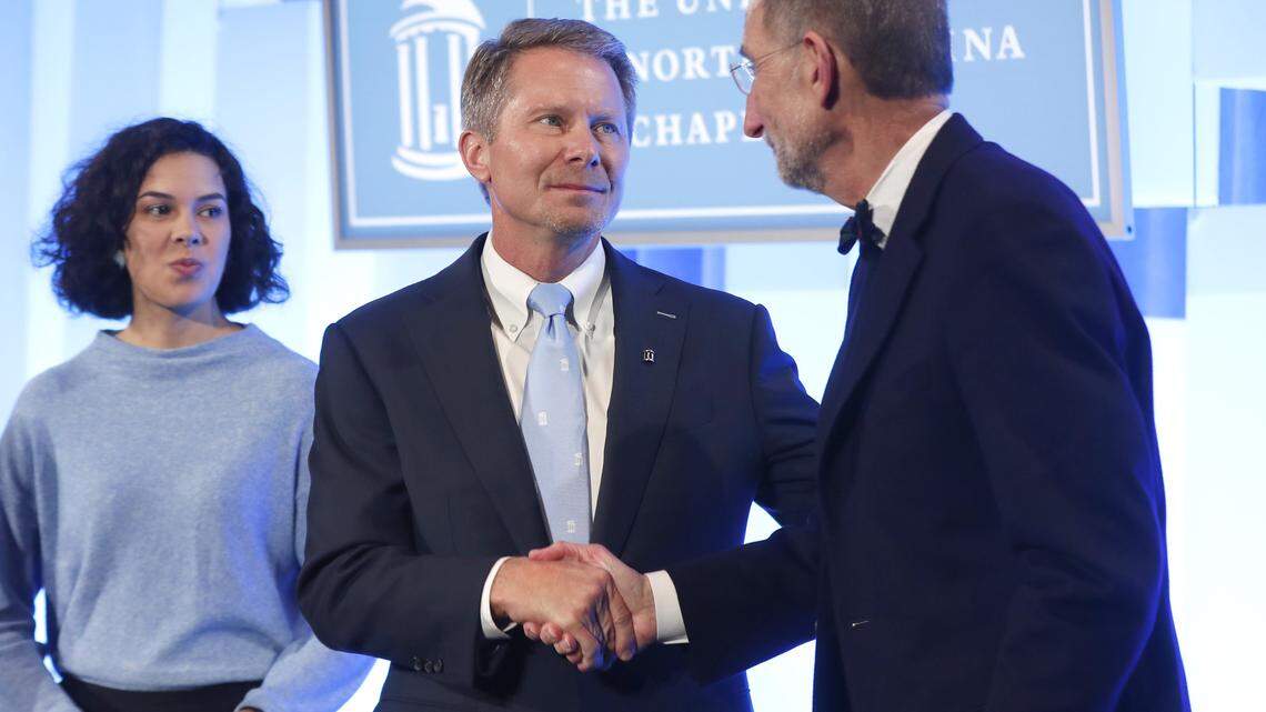 UNC System Interim President Bill Roper, right, shakes hands with Kevin Guskiewicz after a ceremony in Chapel Hill, N.C. celebrating Guskiewicz being named chancellor of UNC-Chapel Hill Friday, Dec. 13, 2019.