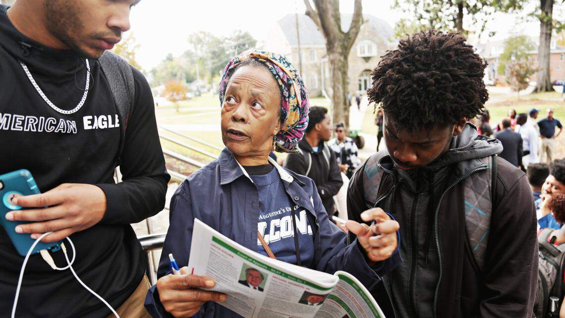 Dr. Iyailu Moses, center, looks over candidates with students George Williams, right, and SaQuad Yeoman, left, before Saint Augustine University’s students marched to the polls on Tuesday, Nov. 6, 2018, at the Tarboro Road Community Center precinct.
