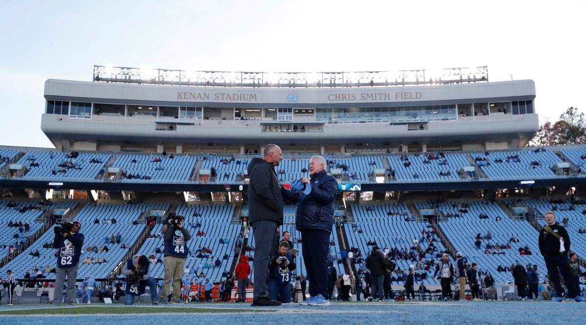 N.C. State head coach Dave Doeren talks with North Carolina head coach Mack Brown before N.C. State’s game against UNC at Kenan Stadium in Chapel Hill, N.C., Saturday, Nov. 30, 2024.