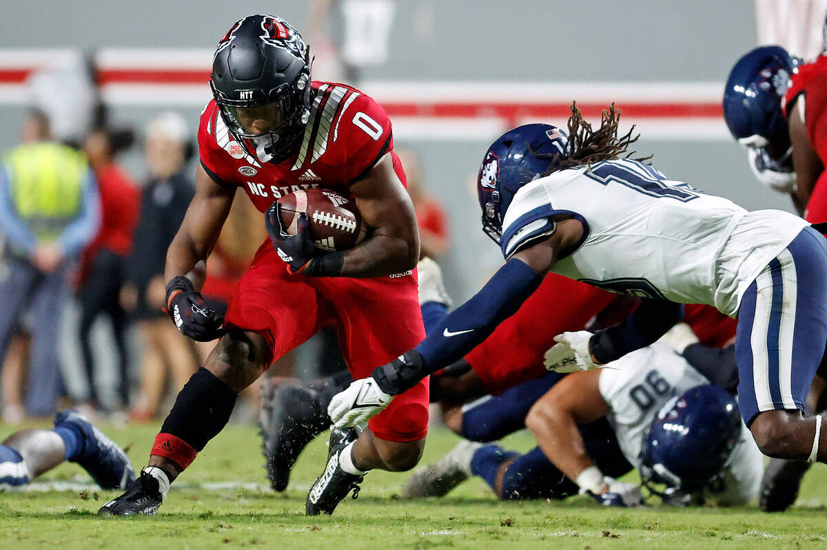 North Carolina State’s Demie Sumo-Karngbaye (0) tries to avoid the tackle of Connecticut’s Malcolm Bell (14) during the first half of an NCAA college football game in Raleigh, N.C., Saturday, Sept. 24, 2022.