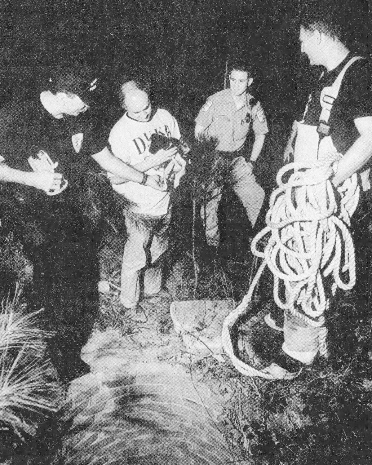 Firefighter Frank DeLucia, left, helped rescue two puppies from a dry 20-foot well near Hope Valley Farms in this 1994 photo. Also in the photo are Chris Miller, Durham Animal Control officer Chris Chappell and Captain Mike Rose.