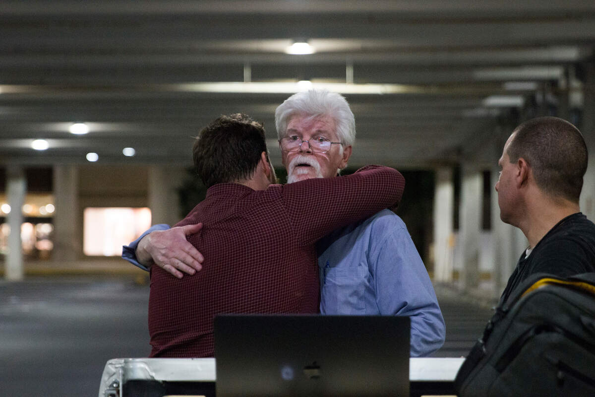 In this Thursday, June 28, 2018 photo, The Capital Gazette reporters Pat Furgurson, center, and Chase Cook hug at a makeshift office in a parking garage of a mall in Annapolis, Md., during coverage of the fatal shootings that happened in their paper's newsroom earlier in the day.