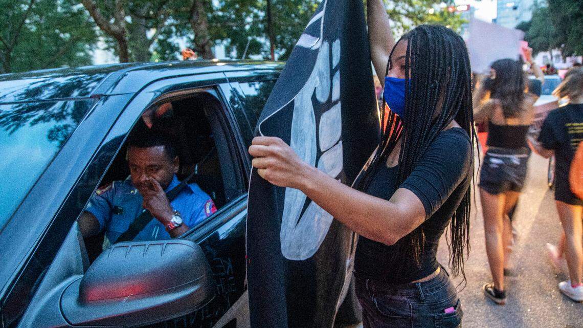 Lauren Howell talks to a Raleigh Police officer in an unmarked vehicle during a march and protest against systemic racism in downtown Raleigh Friday, Aug. 28, 2020. The RPD is one of dozens of departments in NC that used the Clearview facial recognition app.