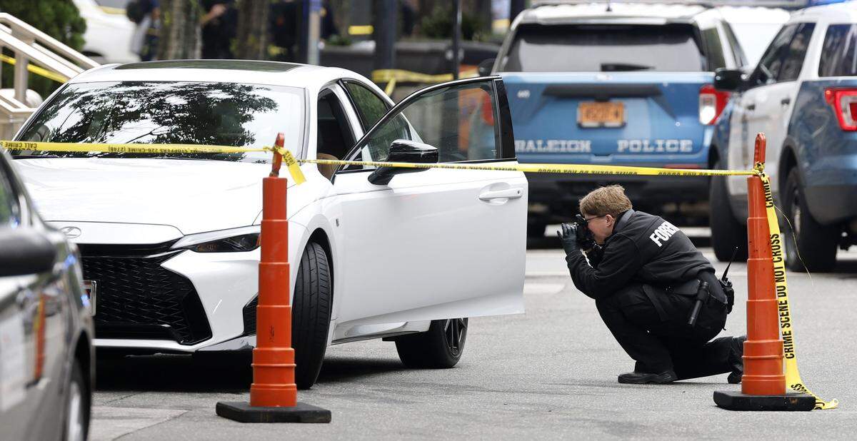 Police take photos of a vehicle on Fayetteville St. in downtown Raleigh Friday morning, May 22, 2026. According to Raleigh police, a suspect is in custody after allegedly shooting two individuals involved in a Wake County court case in downtown Raleigh.