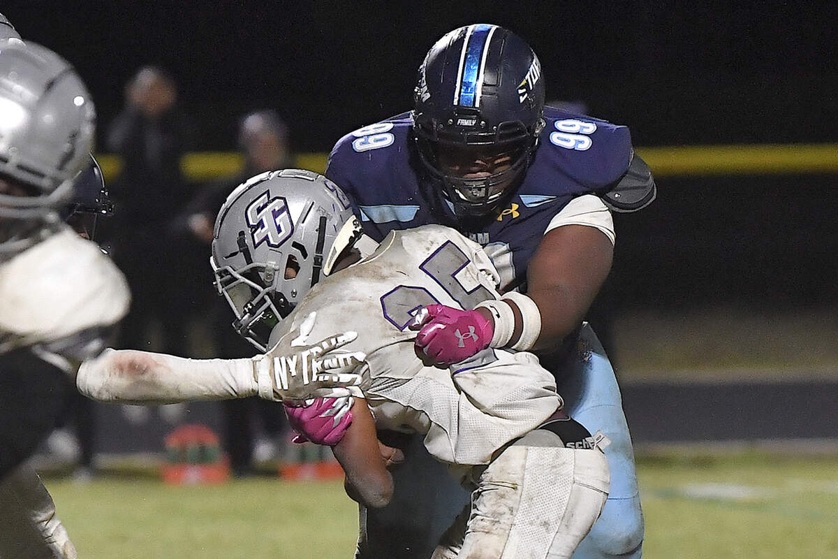 Willow Spring’sJaveion Matthews (99) grapples South Garner’s Micah Scurlock (25) stopping a late game touchdown in the fourth quarter. The Willow Spring Storm and the South Garner Titans met in a football game in Fuquay-Varina. N.C. on October 18, 2024.