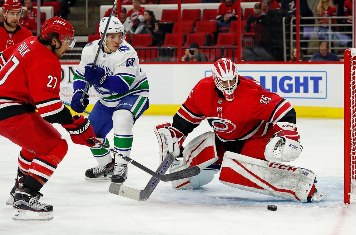 Carolina Hurricanes goaltender Curtis McElhinney (35) blocks a shot as Vancouver Canucks’ Bo Horvat (53) and Carolina Hurricanes’ Justin Faulk (27) look for a rebound during the first period Oct. 9, 2018, in Raleigh, N.C.