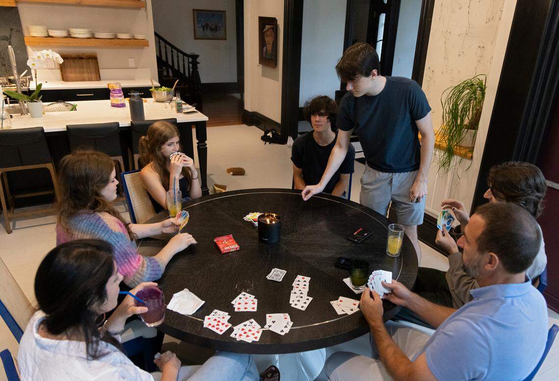 Tina Konidaris and Jeff Turpin play cards with their children, from left, Melina Kuehn, 16, Talia Kuehn, 13, Asher Turpin, 16, Andrew Turpin, 19, and Alexander Turpin, 17, as dinner cooks at the Andrews-Duncan House on Thursday, May 25, 2023, in Raleigh, N.C. The family moved into the nineteenth century house in February after spending about five years renovating it.